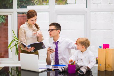 Güzel Müdürü telefonu tutar ve küçük oğlu oturur ve çalış, ofiste bir masada oturur onun Yöneticisi için açılan bir klasörü gösterir