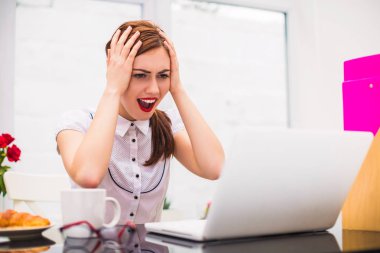 Ofisinde masada oturur ve laptop genç sürpriz ofis çalışanı portresi