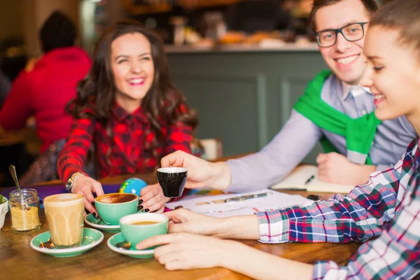 在休息的时候 微笑的人们坐在桌旁 喝着几杯咖啡 在咖啡馆里 — 图库照片