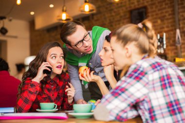 Grup öğrenci masada oturur, telefonda konuşmak, diğerleri konuşmada bir kafede bir ara zaman dinle