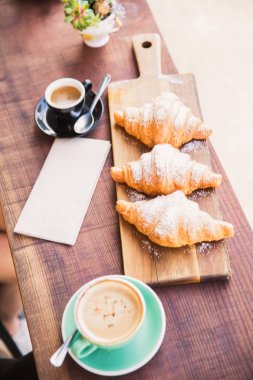 Kruvasan ve kahve masada kafe penceresinde yakın:
