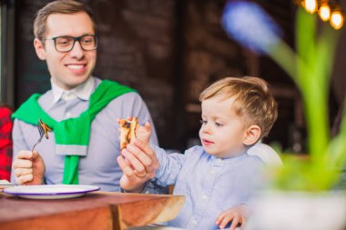 Portre, baba ve oğul sit masada gülümseyen baba oğula restoranda dilim elmalı verir