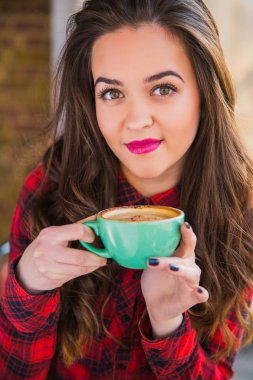 Genç ve güzel kadın portre ellerini, kafede kahve tutar