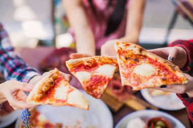 Bir restoran tabloda ötesinde insanların yakın çekim üç dilim pizza tutmak