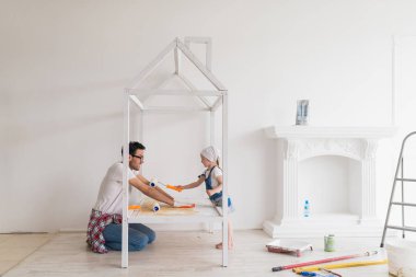 Evde tamir ediyorsun onun küçük kızı ile genç mutlu baba yan görünüm, mutlu kızı babası silah panel yardımı ile boyar.