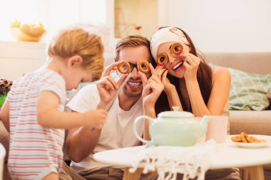 Masada oturan ve simit odasında bakarak mutlu anne yakınındaki küçük oğulları oynayan