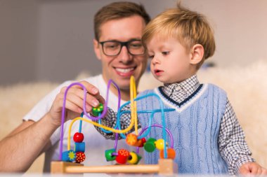 Oyuncak gülümseyen babası evde yakınındaki gelişmekte olan ile oynarken küçük şirin ciddi oğlu
