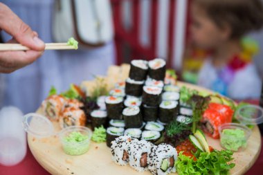 Yakın çekim farklı suşi bir tepsi ve bu yeme insanlar