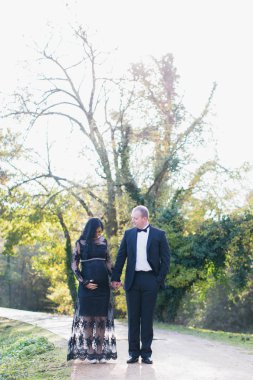 Hamile bir kadın parkta mutlu kocası ile standları ve eller birbirlerini tutuyorlar