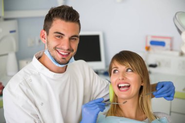 dişçi aynası ile hasta bakarak gülen bir görüntü.