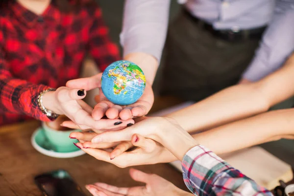 The globe in hands of people, person keeps a pen which she shows on the globe, indoors