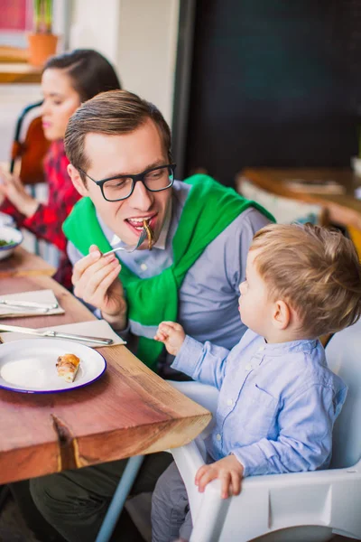 クローズ アップ父の座っている彼の息子を持つテーブルで 父は食事のスライスを刺さ 息子がレストランでの彼の父を見て — ストック写真