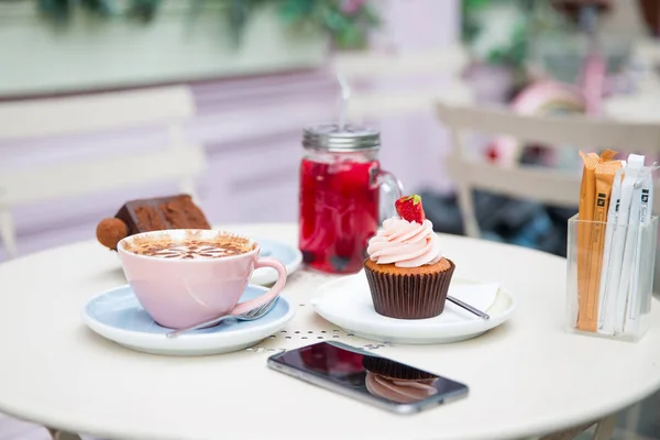 Photography of cakes, cappuccino, cocktail and phone on a table