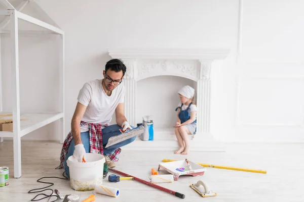 Jovem Homem Sério Faz Reparação Casa Sua Filha Senta Atrás — Fotografia de Stock