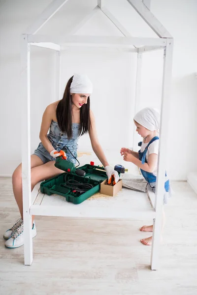 Young Happy Mother Sits Crib Instruments Repair Her Daughter Stands — Stock Photo, Image
