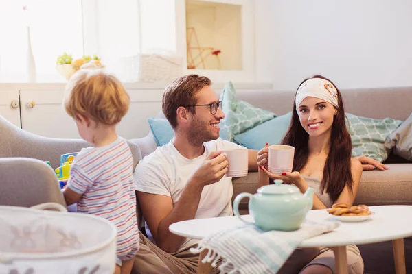 Young Happy Parents Sitting Table Room Keeping Cups Tea Little — Stock Photo, Image