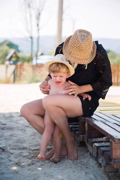 Joven Madre Sentada Manteniendo Pequeño Hijo Caprichoso Con Protector Solar — Foto de Stock
