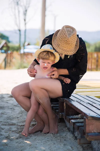 Jovem Mãe Sentada Mantendo Seu Pequeno Filho Caprichoso Praia — Fotografia de Stock