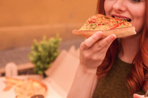 Close-up a piece of pizza which young woman biting