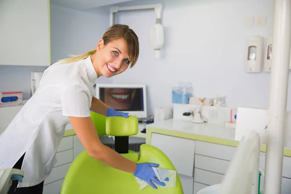 Smiling woman dentist cleaning up dentist chair after procedures.