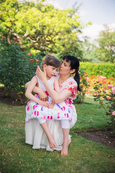 Bahçede oturma ve güzel Engelli kızı kucakta tutan genç mutlu anne