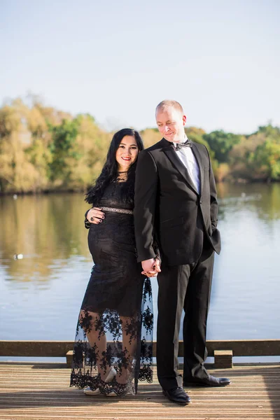 一个怀孕的温柔的女人和她的丈夫站在池塘的背景下 他们互相牵手 — 图库照片
