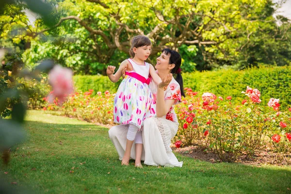 Bahçede oturma ve onun büyüleyici tutan genç mutlu anne kızı ve ona bakıyor ve gülümsüyor devre dışı