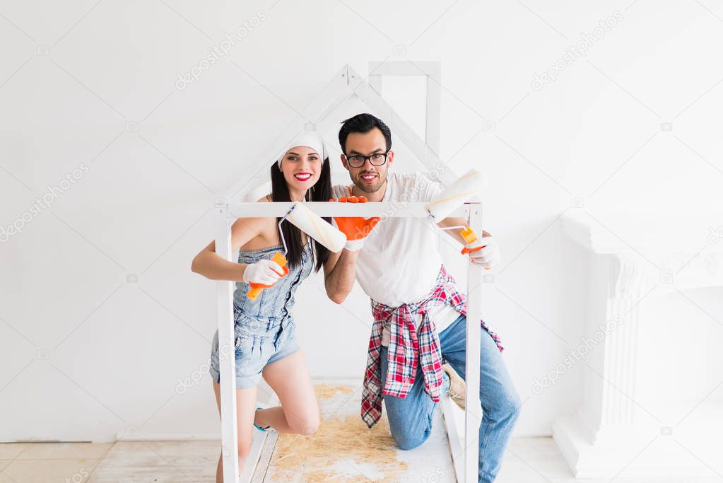 The young happy couple draws crib with help of platens at home