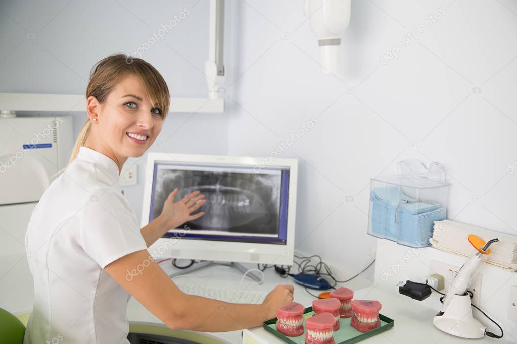 Woman dentist looking at panoramic dental x-ray. Computer screen and film.