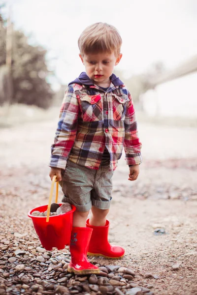 Lindo Niño Pie Aire Libre Sosteniendo Cubo Rojo Con Piedras —  Fotos de Stock