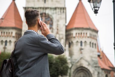 Eski Gotik yapı açık arka planı telefonla konuşan zarif genç adam arkadan görünüm