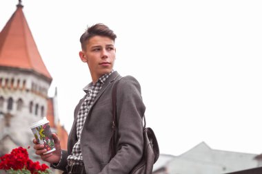 Açık duran ve kahve fincanı tutan ve bir kenara arayan genç adam yan görünüm