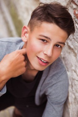 Mutlu genç adam açık eski evin duvarının yakınında oturuyor Close-up