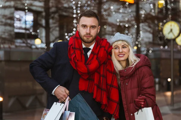 带着购物袋站在大街上的幸福年轻夫妇的肖像 — 图库照片