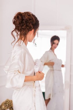 Güzel genç gelin kapalı aynanın önünde duran ve gelin elbisesi holding