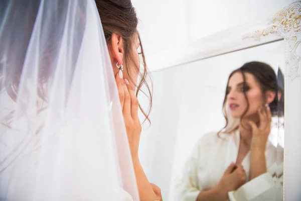 美しく幸せな花嫁ベールに鏡の前に立って 鏡を見て — ストック写真