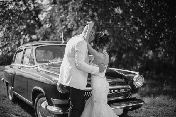 幸せな新婚の夫婦が一緒に立っている古い車に近い屋外 — ストック写真