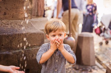 Açık havada ellerinden su içen sevimli küçük çocuğun portresi