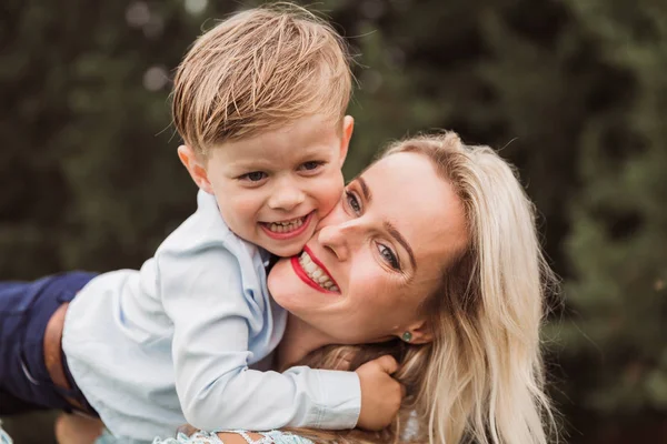 屋外で彼女の小さな笑顔の息子を抱きしめるエレガントな幸せな若い女性をクローズアップ — ストック写真