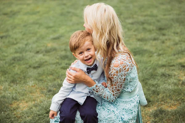 Jovem Mulher Elegante Sentado Grama Livre Segurando Seu Pequeno Filho — Fotografia de Stock