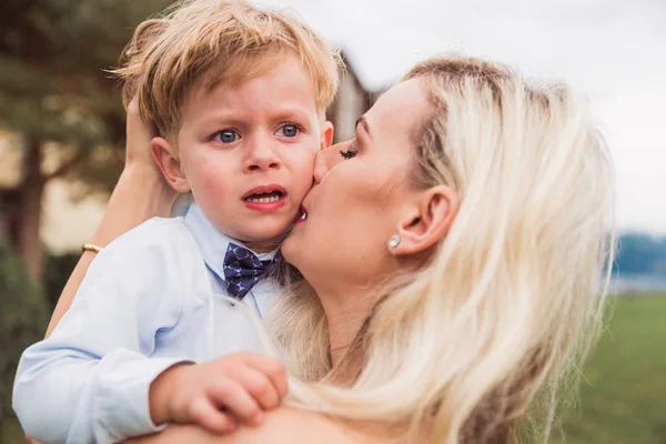 Close-up the loving mother who is calming her little son who is crying outdoors