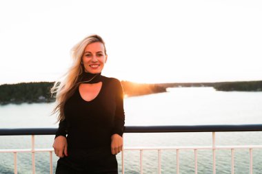 Denizin arka planına karşı gemide duran gülümseyen genç kadının portresi