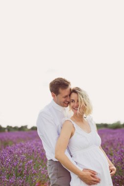 Yakışıklı genç adam, keyifli hamile karısıyla lavanta tarlasında kaliteli zaman geçiriyor.