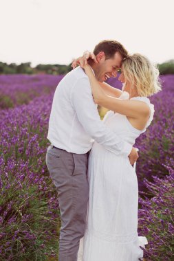 Mutlu genç adam, keyifli hamile karısıyla lavanta tarlasında kaliteli zaman geçiriyor.