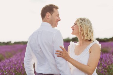 Genç adam, çekici hamile karısıyla lavanta tarlasında dikilip ona bakıyor.