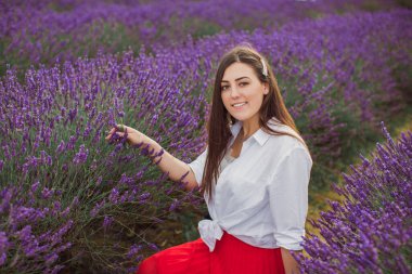 Lavanta tarlasında oturan neşeli, genç ve güzel esmerin portresi.