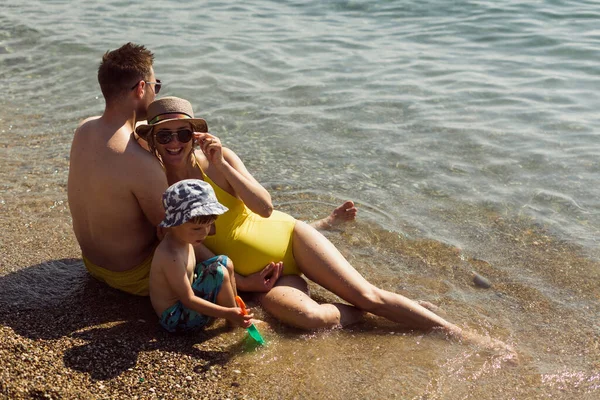 Jovem Família Grávida Feliz Sentada Junto Oceano Relaxando — Fotografia de Stock