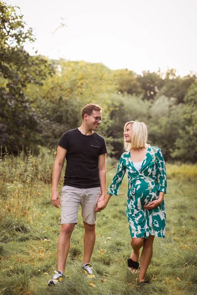 幸せな妊娠中の夫婦が庭を歩いている — ストック写真