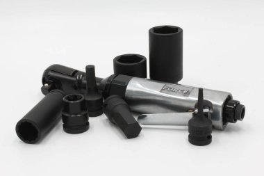 Pnömatik bir kilit anahtarı ve beyaz arka plana saçılmış çeşitli siyah soketler. İzole araçlar ürün tanıtımı, e-ticaret ve otomotiv veya endüstriyel bakım ve onarım hakkında içerik için idealdir..