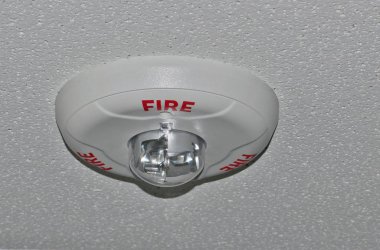 Bir ofis tavan bağlı strobe ile dairesel gri yangın alarmı.